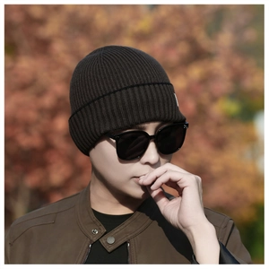 Close-up of deep brown ribbed knit beanie with stylish logo patch on a male model