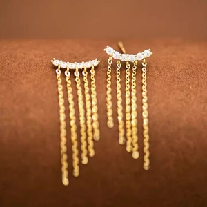 Detail of elegant gold tassel earrings with sparkling zircon stones and layered chains