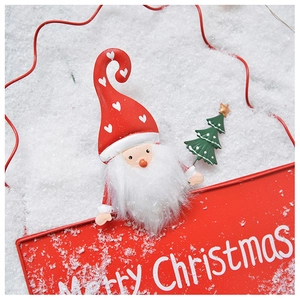 Close-up of Merry Christmas metal plaque with Santa and tree motifs in festive colors