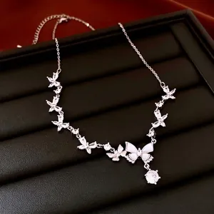 Silver butterfly necklace with zircon stones and adjustable chain on leather tray