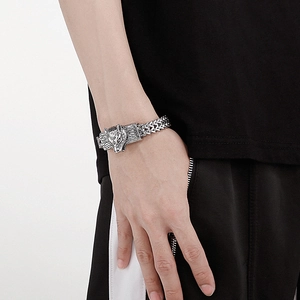 Detail of retro silver stainless steel wolf head bracelet with rugged woven chain design