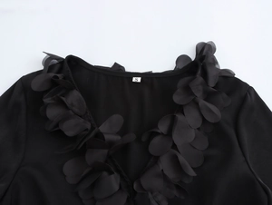 Close-up of elegant V-neckline with 3D floral petals on a stylish black blouse