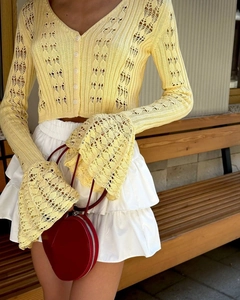 Detail of hollow knit cardigan featuring V-neck buttons and stylish long flared sleeves