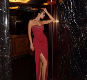 Detail of red strapless satin gown featuring sparkling sequins and a high leg slit