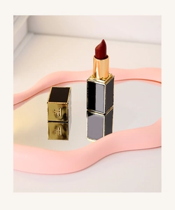 Macro detail of luxury lipstick case showing the embossed logo and reflective pink mirror