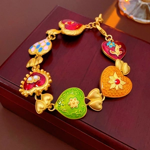 Macro shot of gold-plated chain bracelet with colorful enamel heart charms on wood box