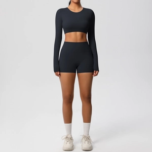 Front view of black long sleeve crop top and high waist shorts yoga set on model