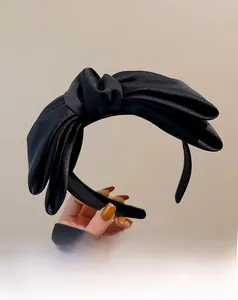 Nahaufnahme eines schwarzen Satin-Haarreifs mit großer Schleife und eleganten Faltenstrukturen