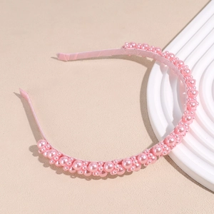 Detail of pink pearl headband with varied sizes on a minimalist display tray