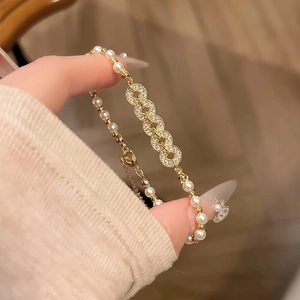 Detail of gold pearl bracelet featuring zircon-encrusted links and lobster clasp closure