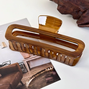 Detail of a brown tortoiseshell rectangle hair claw clip with cutout design on a table