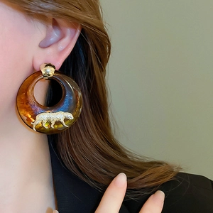 Detail of amber resin hoop earring featuring a gold leopard motif and micro-set zircon