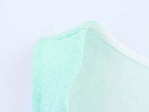 Close-up of light green tweed fabric texture and neckline detail on sleeveless dress