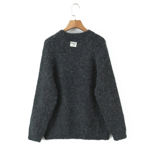 Detail of grey crewneck knit sweater with long fuzzy texture and designer label on hanger