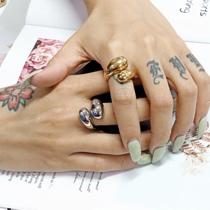 Minimalistische Tropfenringe in Gold und Silber auf einer Hand mit grünen Nägeln