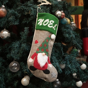 Grey knit Christmas stocking featuring a red gnome and Noel embroidery on a festive tree