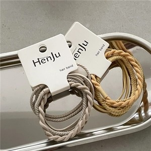 Detail of twisted grey and beige elastic hair bands displayed on a metal tray