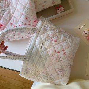 Detail of quilted cotton floral tote bag featuring a decorative pink ribbon and fabric label
