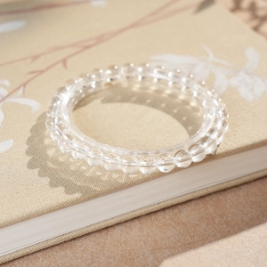 Detailed close-up of clear crystal beaded bracelet on linen background with natural light