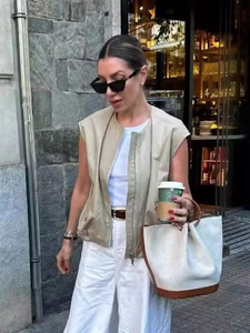 Schicke Damenweste in Khaki mit Reißverschluss, weißer Hose und modischer Beuteltasche