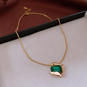 Close-up of emerald cut green gemstone pendant with gold snake chain necklace