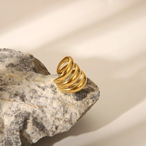 Macro shot of three-layer gold spiral ring resting on a textured gray stone surface