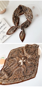 Detail of brown paisley pleated silk scarf tied as a bow on a minimalist white surface