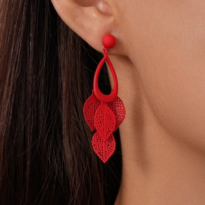 Detailed close-up of red hollow leaf fringe earrings worn by a model in a side view