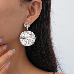 Macro detail of silver geometric earrings with woven texture on elegant female model