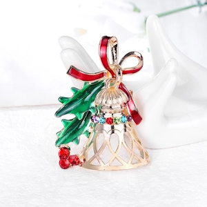 Christmas bell brooch with red bow and colorful rhinestones on elegant white surface