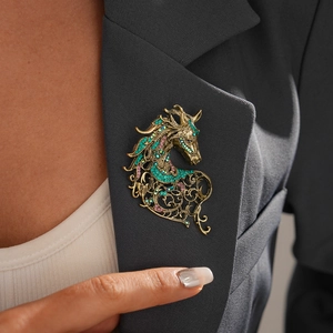 Detailed macro of vintage dragon brooch with green crystals on dark grey blazer