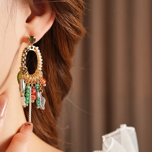 Detail of vintage leaf tassel earrings with colorful beads and dark gemstone on model