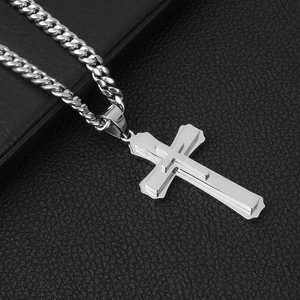 Macro view of layered silver stainless steel cross pendant on a thick Cuban chain link