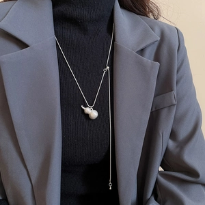 Dettaglio ravvicinato della collana con ciondolo Wu Lou spazzolato e nappe su maglione scuro