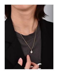 Detail shot of a minimalist gold necklace with a round pearl pendant on a model's neck
