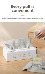 Detail view of microfiber cleaning cloths in a white dispenser box on a wood table