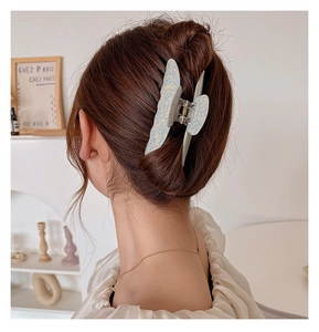 Blue butterfly hair claw clip with white dots worn on hair in a stylish side view