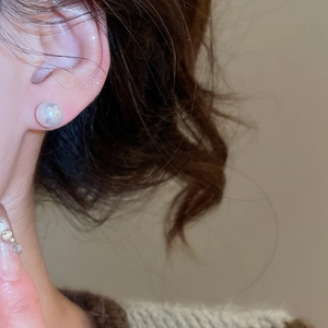 Gros plan d'un clou d'oreille en perle de résine blanche ronde sur l'oreille