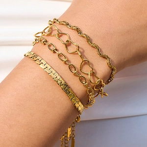 Set of four gold stainless steel bracelets with heart charms and various chain designs