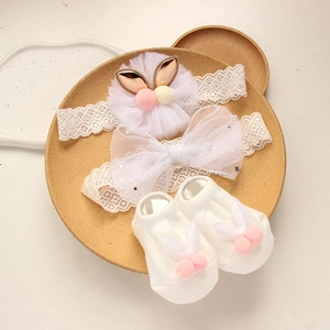 Detail of white lace baby headbands and matching socks with cute rabbit ear decor