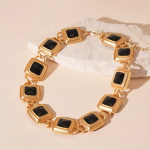 Close-up of vintage golden square links necklace with black resin inlay on stone