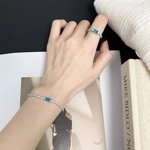 Silver jewelry set with blue square gemstones on hand model for an elegant aesthetic