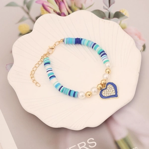 Close-up of blue clay disc bracelet with heart enamel pendant and sparkling crystals