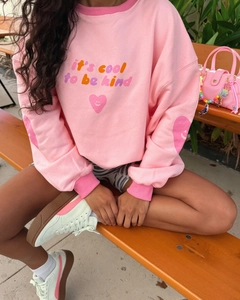 Detail shot of pink long sleeve sweatshirt with 'it's cool to be kind' slogan print