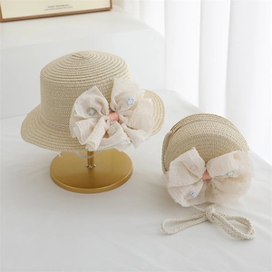 Détail d'un ensemble chapeau et sac en paille avec dentelle et nœud fleuri pour filles