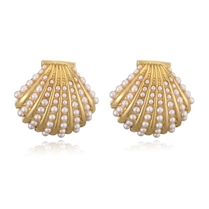 Detailed macro view of scallop shell stud earrings featuring white pearls and gold base