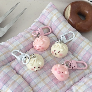 Cute cartoon dumpling bun keychains with pig and bear designs on a checkered mat