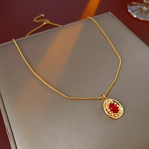 Detail of vintage oval gold necklace with red gemstone pendant on display box