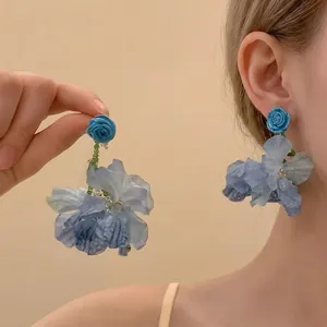 Détail de boucles d'oreilles fleurs en tissu bleu avec rose 3D et texture pétale