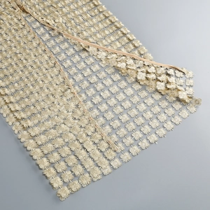 Detail view of golden floral hollow lace fabric and metallic zipper on two-piece set